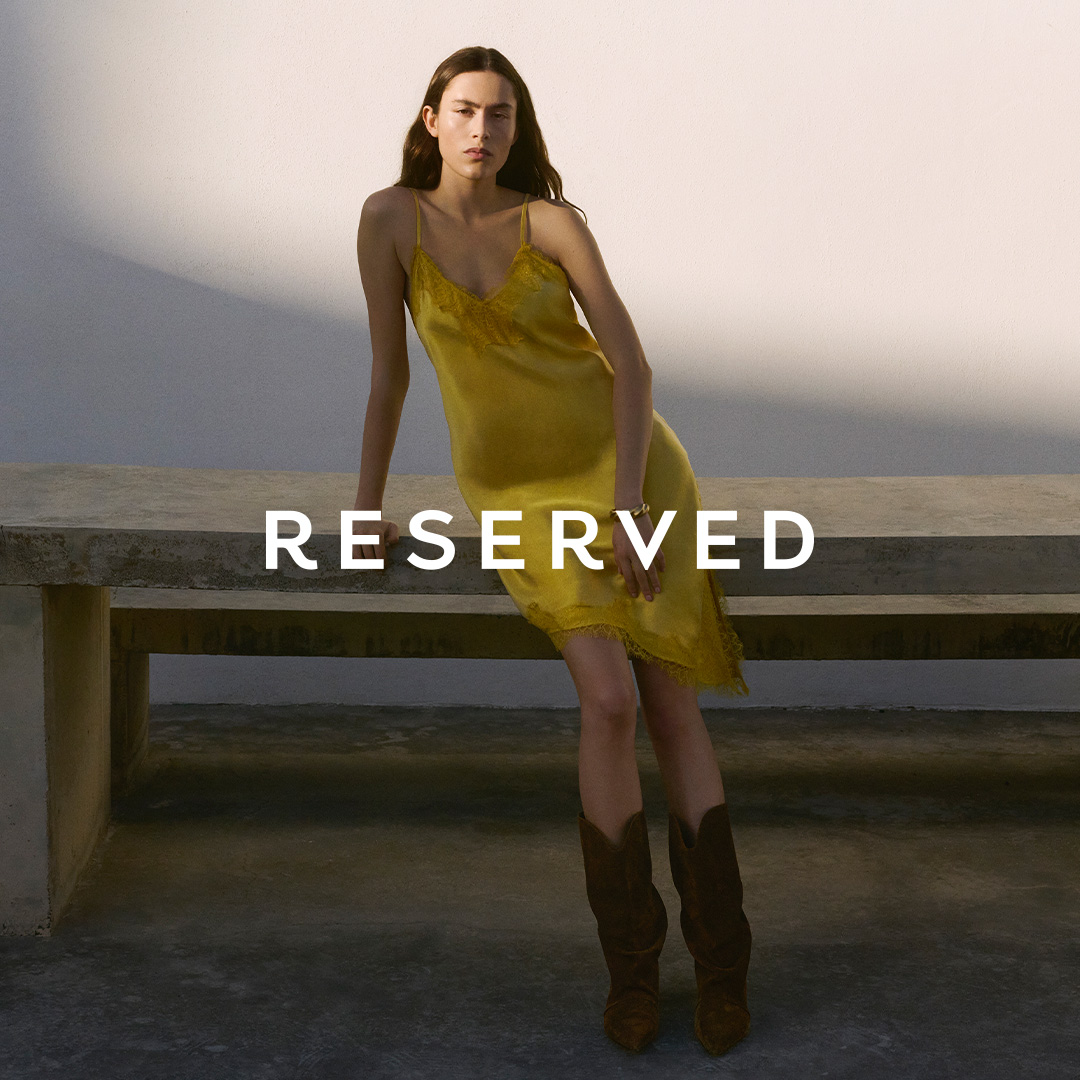 Modelka w żółtej sukience na tle betonowej ławki