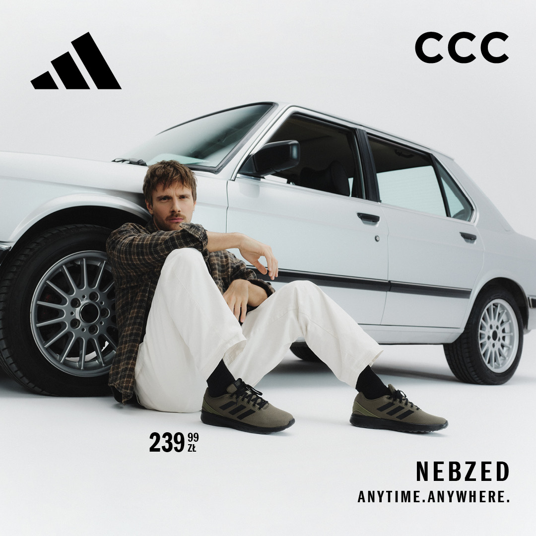 Mężczyzna w butach Adidas Nebzed siedzi przy białym samochodzie.